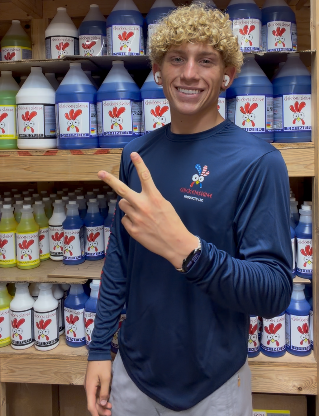 Person in a blue shirt standing in front of shelves with bottles in a store.